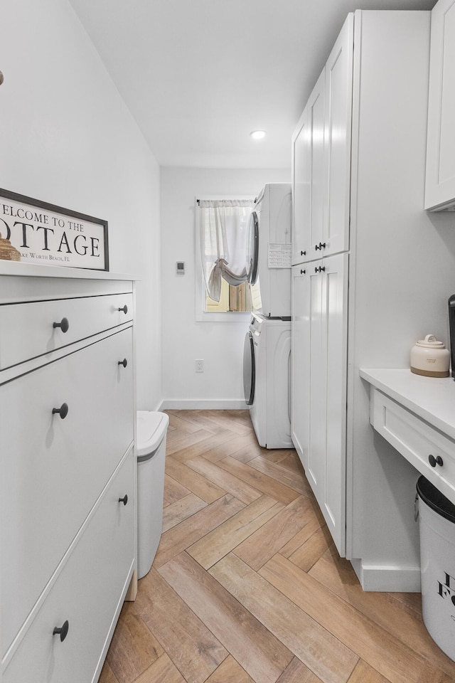 laundry area with cabinets, stacked washing maching and dryer, and light parquet floors