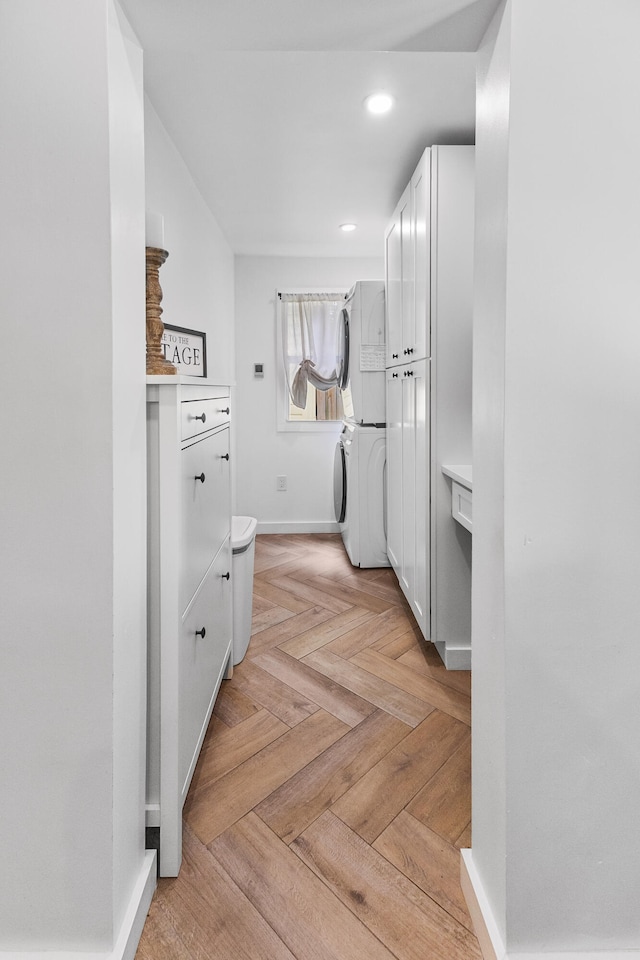 hallway featuring stacked washing maching and dryer and light parquet flooring