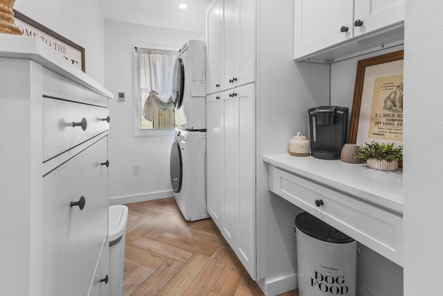 laundry room featuring cabinets, stacked washing maching and dryer, and light parquet floors