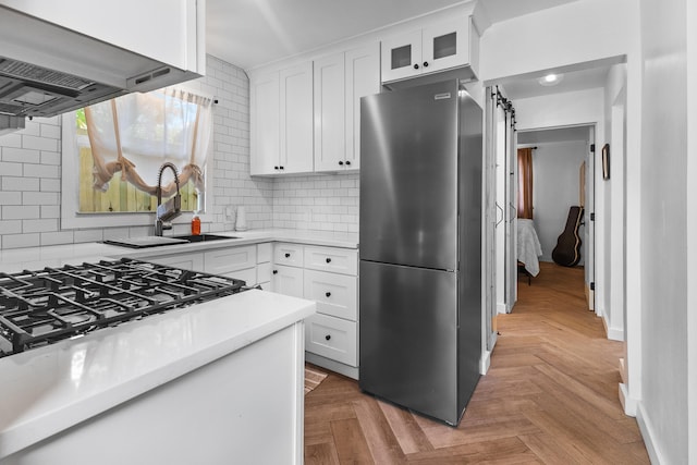 kitchen with white cabinets, decorative backsplash, ventilation hood, and stainless steel fridge