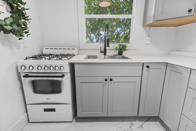 kitchen featuring gray cabinets, sink, and gas range gas stove