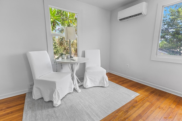 sitting room featuring hardwood / wood-style flooring and a wall mounted air conditioner