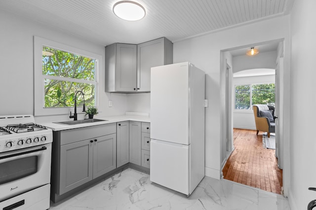 kitchen with sink, light hardwood / wood-style flooring, gray cabinetry, and white appliances