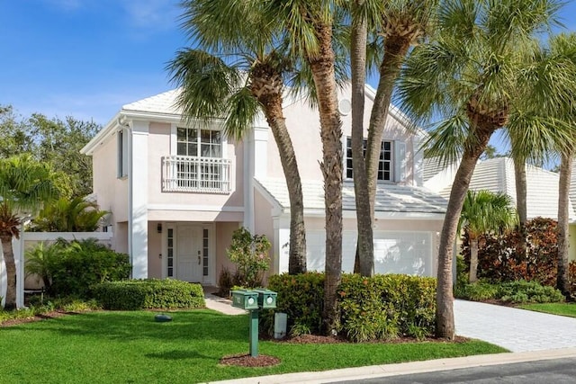 view of front of house featuring a front lawn, a balcony, and stucco siding