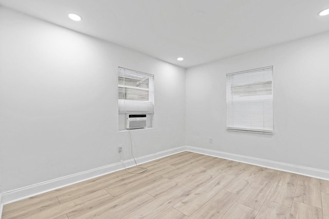 unfurnished room featuring cooling unit and light hardwood / wood-style floors