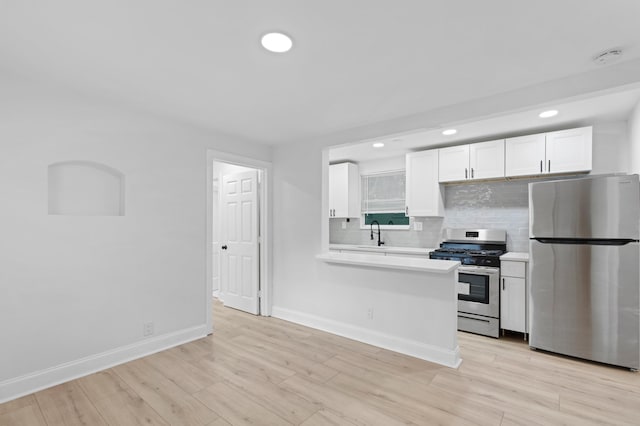 kitchen with light wood-type flooring, white cabinetry, backsplash, stainless steel appliances, and sink