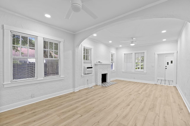 unfurnished living room featuring ornamental molding, a brick fireplace, cooling unit, ceiling fan, and light hardwood / wood-style floors