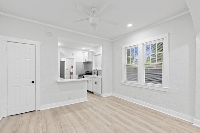 spare room with crown molding, light wood-type flooring, sink, and ceiling fan