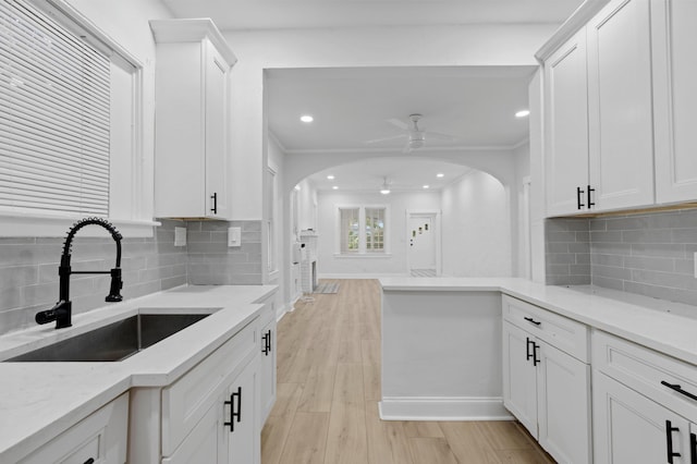 kitchen with light hardwood / wood-style flooring, sink, ceiling fan, light stone counters, and white cabinets