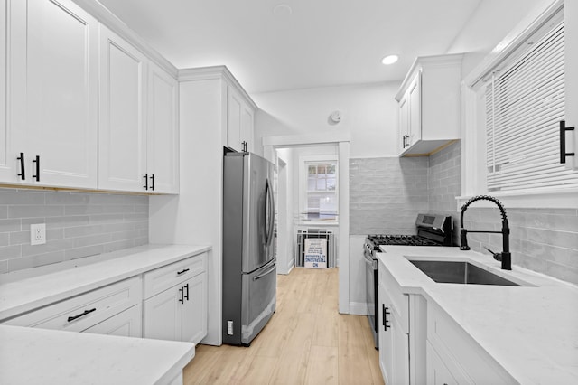 kitchen with backsplash, light wood-type flooring, appliances with stainless steel finishes, and white cabinets