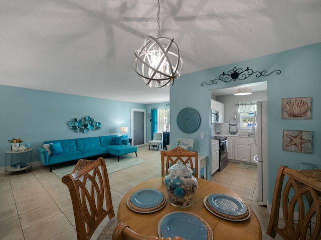 dining area with a textured ceiling, a notable chandelier, and light tile patterned floors