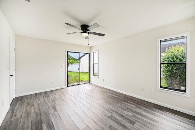 empty room featuring ceiling fan, hardwood / wood-style flooring, and a wealth of natural light