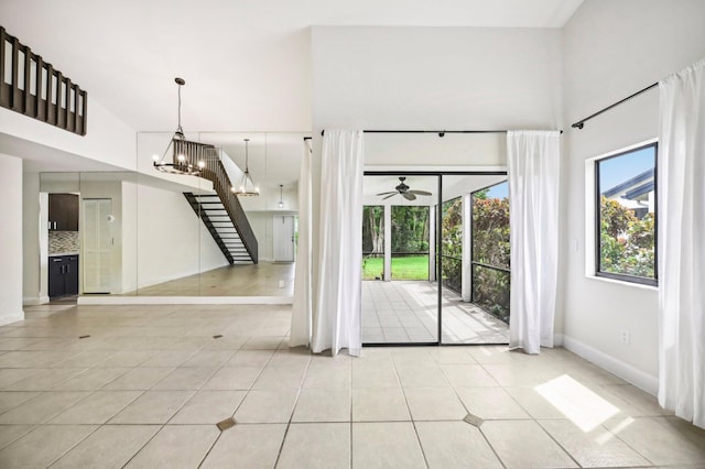 interior space with ceiling fan with notable chandelier, a towering ceiling, and light tile patterned floors