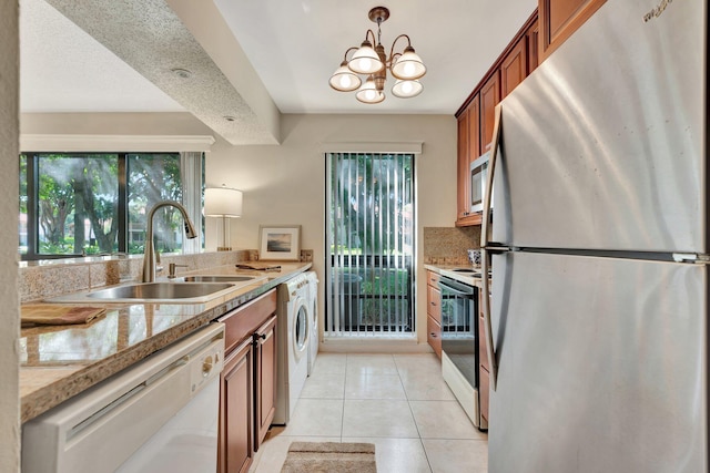 kitchen with stainless steel appliances, sink, light tile patterned floors, a chandelier, and hanging light fixtures