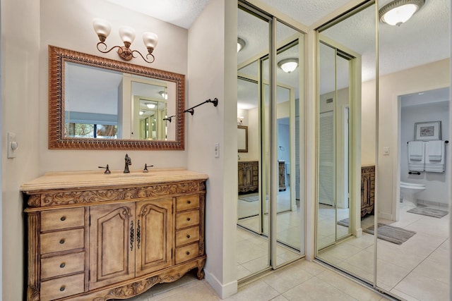 bathroom with tile patterned flooring, vanity, toilet, and a textured ceiling