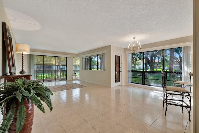 interior space with a textured ceiling, an inviting chandelier, and light tile patterned flooring