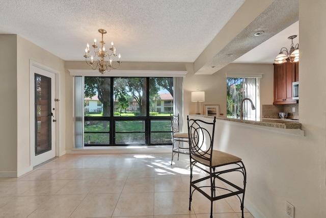 tiled dining area featuring a notable chandelier, sink, and a textured ceiling