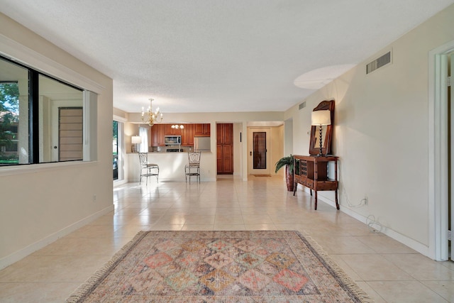 interior space with light tile patterned floors, a textured ceiling, and a chandelier