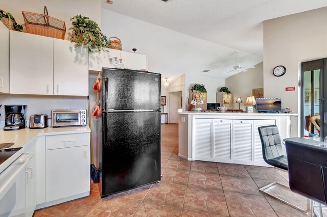 kitchen featuring ceiling fan, white cabinets, black refrigerator, white range oven, and vaulted ceiling