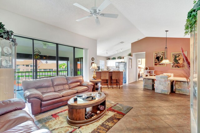 tiled living room featuring vaulted ceiling, ceiling fan, and a textured ceiling