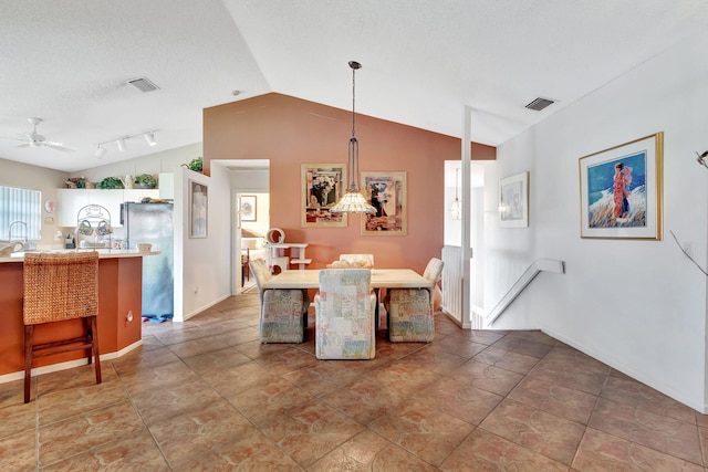 dining area with a textured ceiling, vaulted ceiling, ceiling fan, and track lighting