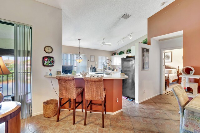 kitchen with a kitchen breakfast bar, a wealth of natural light, kitchen peninsula, and black refrigerator