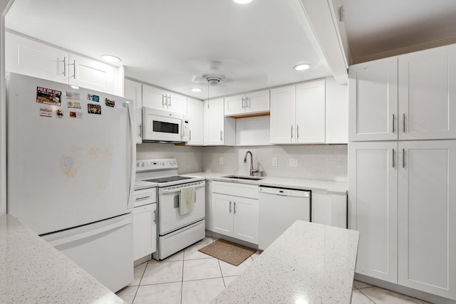 kitchen with white cabinetry, sink, white appliances, and light tile patterned floors