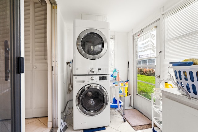 clothes washing area featuring light tile patterned floors and stacked washer / dryer