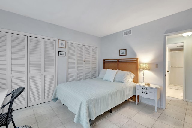 bedroom with light tile patterned floors and multiple closets