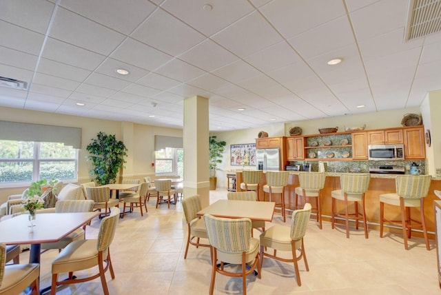 dining area featuring light tile patterned floors, visible vents, and a healthy amount of sunlight