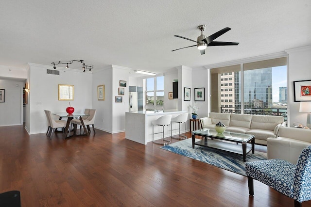 living room featuring ceiling fan, dark hardwood / wood-style floors, crown molding, and a textured ceiling