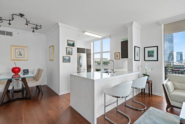 kitchen with stainless steel refrigerator with ice dispenser, sink, a healthy amount of sunlight, and kitchen peninsula