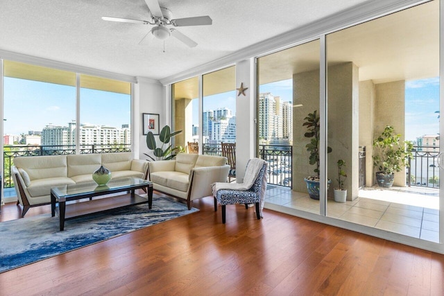 living room with hardwood / wood-style flooring, a textured ceiling, a wall of windows, and ceiling fan