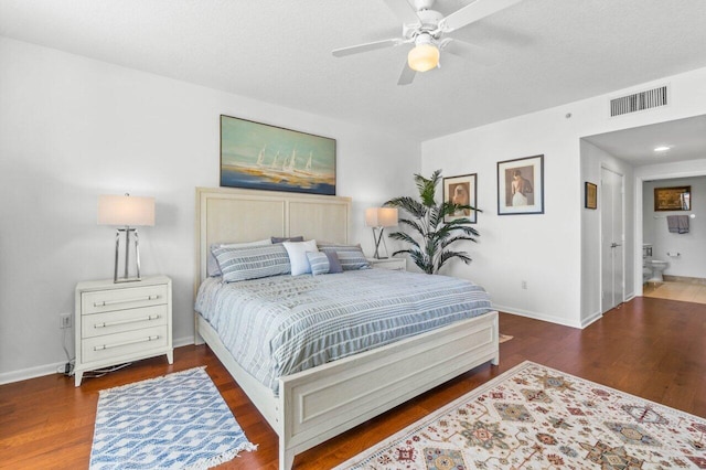 bedroom featuring ceiling fan, a textured ceiling, dark hardwood / wood-style flooring, and ensuite bath