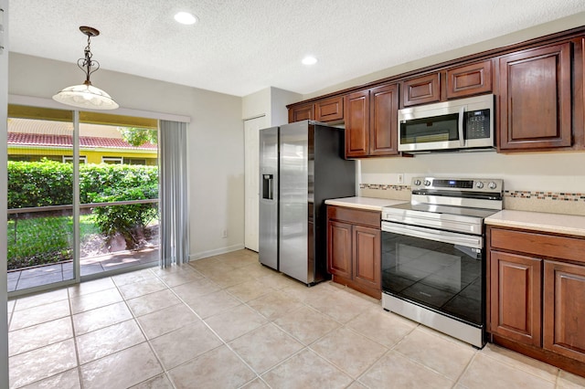 kitchen featuring appliances with stainless steel finishes, hanging light fixtures, a textured ceiling, and light tile patterned floors