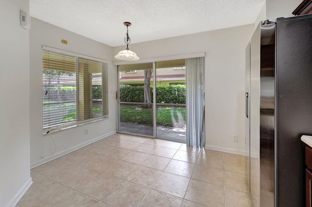 unfurnished dining area featuring a textured ceiling, plenty of natural light, and light tile patterned flooring