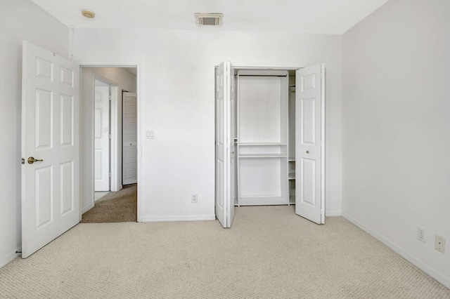 unfurnished bedroom with light colored carpet, a textured ceiling, and a closet