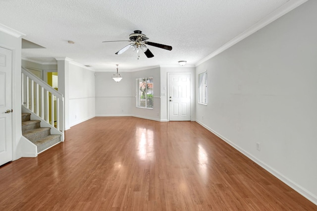 unfurnished living room featuring wood-type flooring, a textured ceiling, crown molding, and ceiling fan