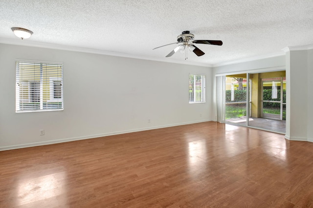 empty room featuring ceiling fan, hardwood / wood-style flooring, a healthy amount of sunlight, and a textured ceiling