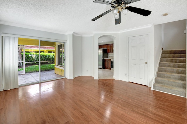 unfurnished living room with ceiling fan, a textured ceiling, light hardwood / wood-style flooring, and crown molding