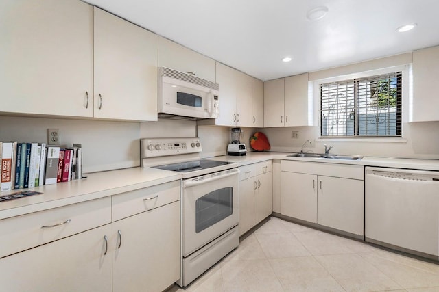 kitchen featuring sink, white appliances, and light tile patterned flooring