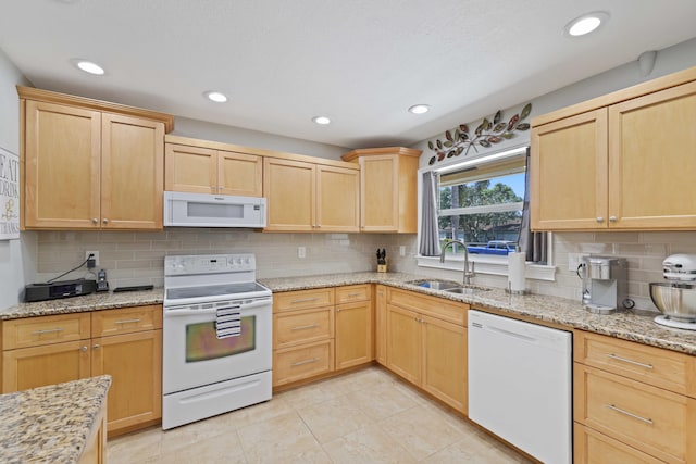 kitchen featuring light brown cabinets, white appliances, sink, and light stone counters