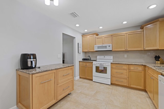 kitchen featuring light brown cabinetry, light stone countertops, tasteful backsplash, and white appliances