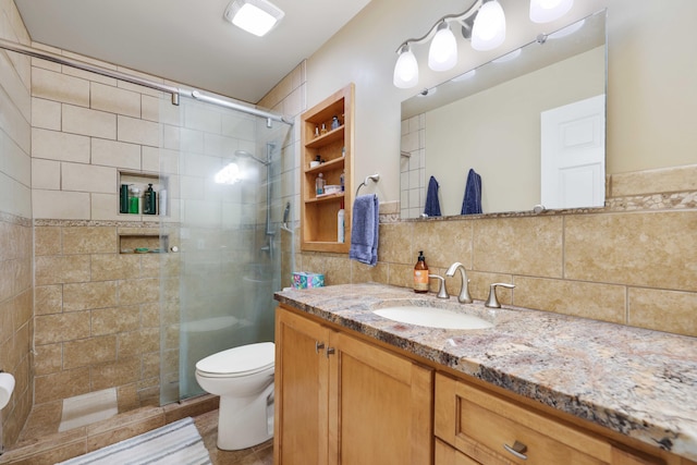 bathroom featuring tile walls, a shower with shower door, backsplash, vanity, and toilet