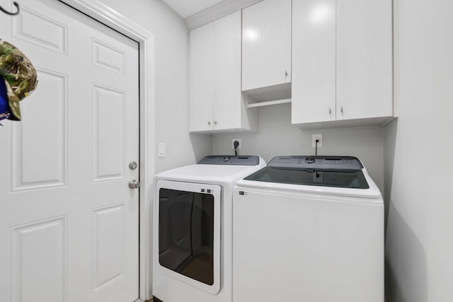 clothes washing area with cabinets and washing machine and clothes dryer