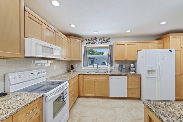 kitchen with light stone counters, light tile patterned floors, sink, white appliances, and light brown cabinetry