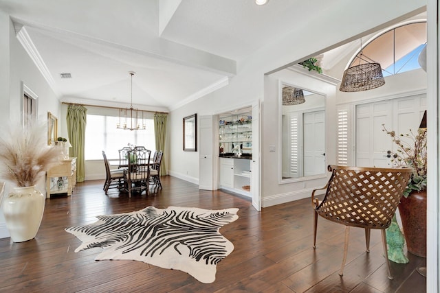 foyer with lofted ceiling, ornamental molding, dark hardwood / wood-style floors, and a chandelier