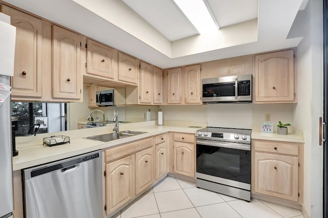 kitchen featuring stainless steel appliances, light brown cabinetry, light tile patterned flooring, and sink