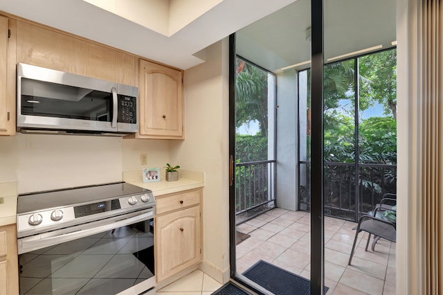 kitchen with light brown cabinets, light tile patterned floors, and stainless steel appliances