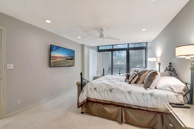 bedroom with ceiling fan, light colored carpet, and a textured ceiling